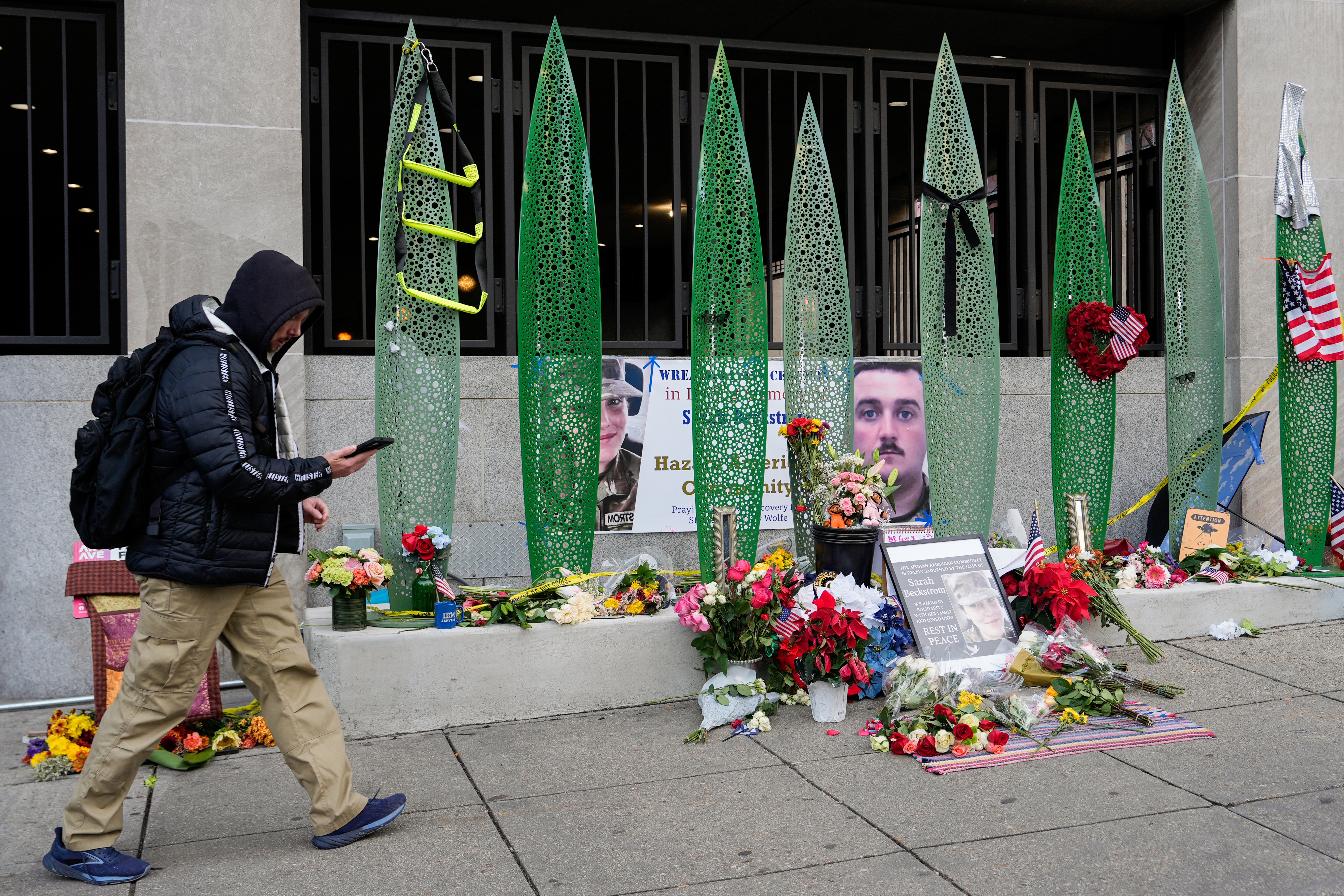 A person walks past a makeshift memorial for U.S. Army Spc. Sarah Beckstrom and U.S. Air Force Staff Sgt. Andrew Wolfe outside of Farragut West Station, near the site where the two National Guard members were shot on Dec. 1 in Washington, D.C.